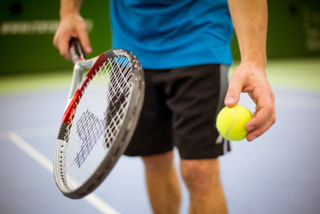 Aktiver Tennisspieler, der einen Tennisball in der Hand hält und den Schläger vorbereitet.