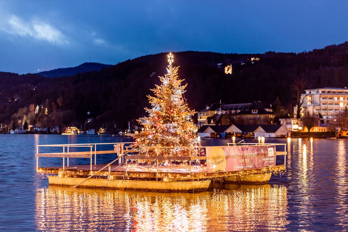Weihnachtsbaum auf einem schwimmenden Ponton am See bei Nacht