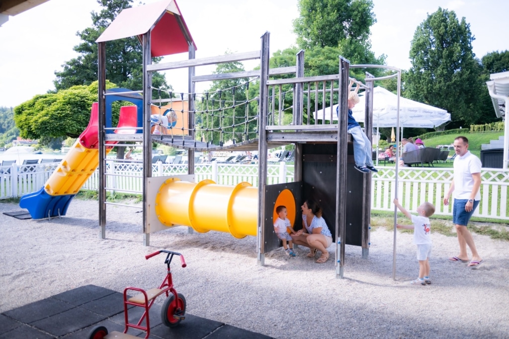 Spielplatz mit Rutsche und Klettergerüst, Kids spielen und Erwachsene beobachten