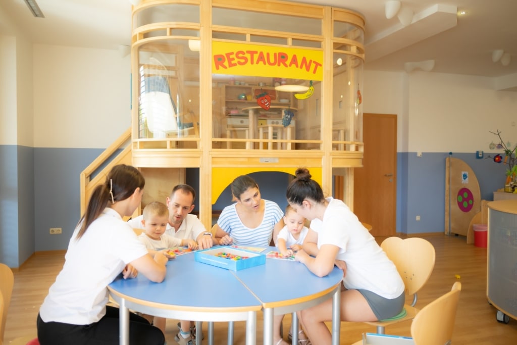 Familie mit Kleinkindern im Spielezimmer beim gemeinsamen Spielen